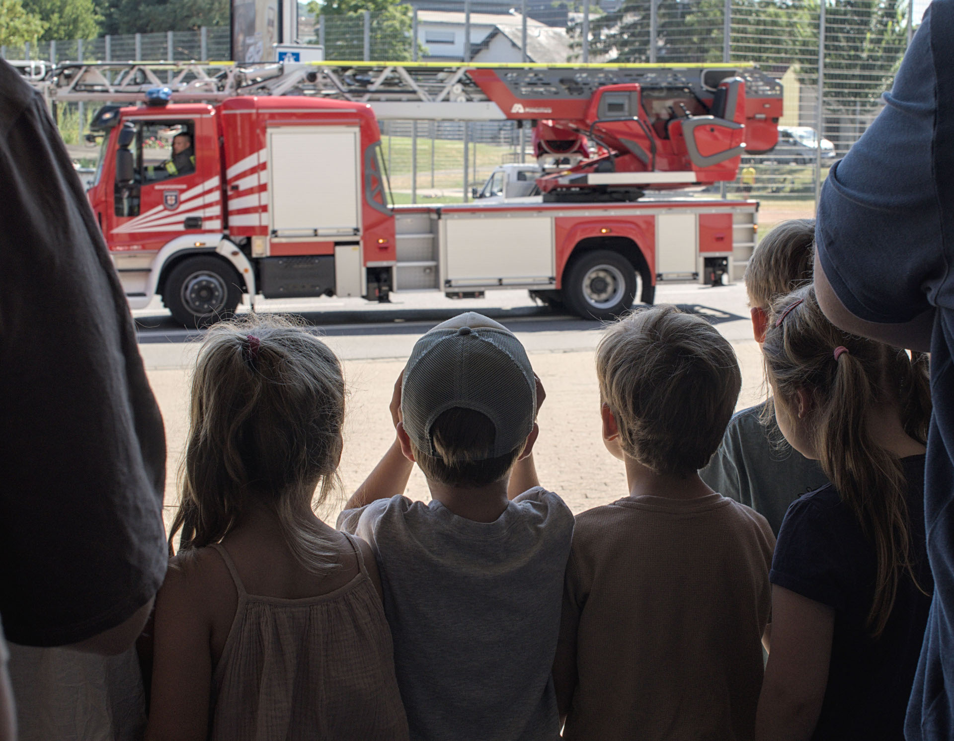 Kinder schauen sich aus der Ferne eine Drehleiter der Feuerwehr an.