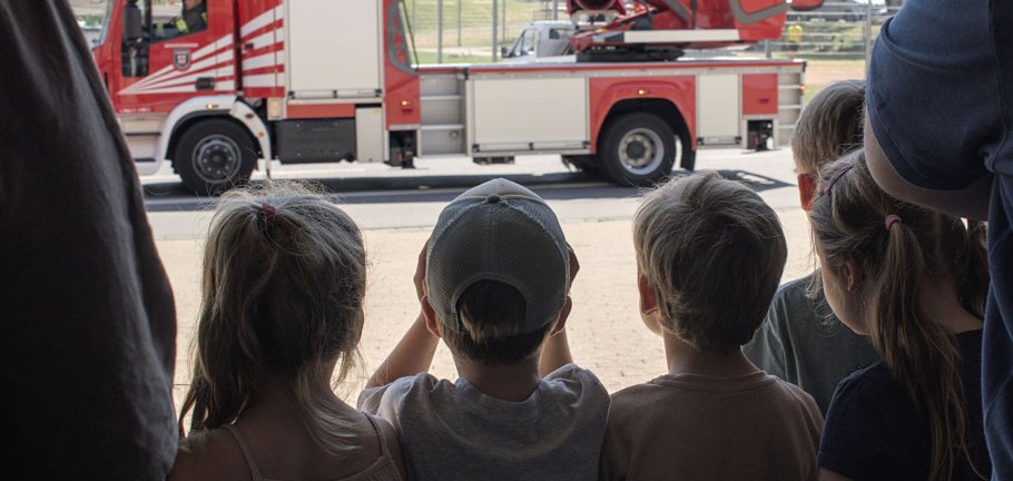 Kinder schauen sich aus der Ferne eine Drehleiter der Feuerwehr an.