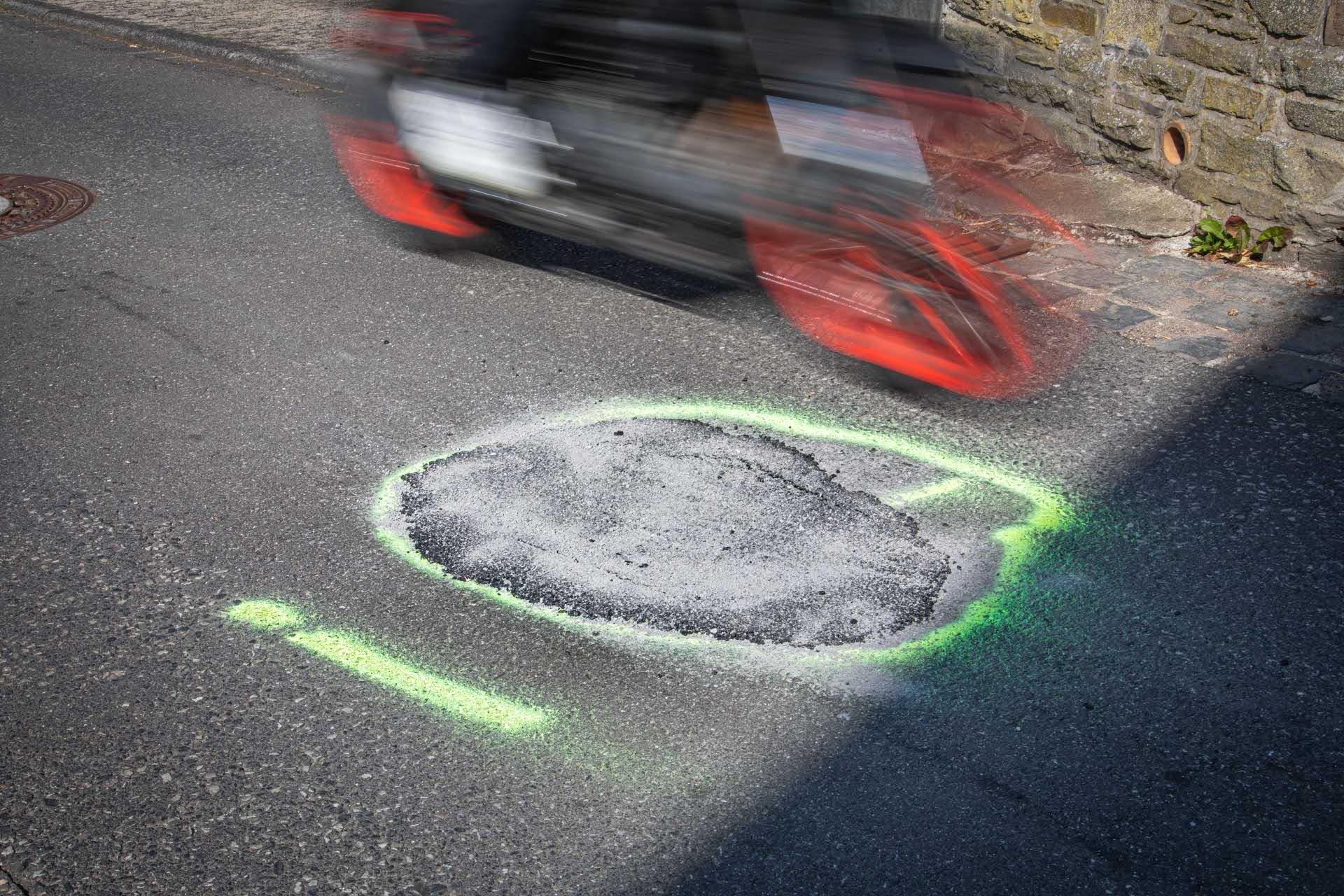 Ein Motorrad fährt an einem Markierung auf der Fahrbahn vorbei.