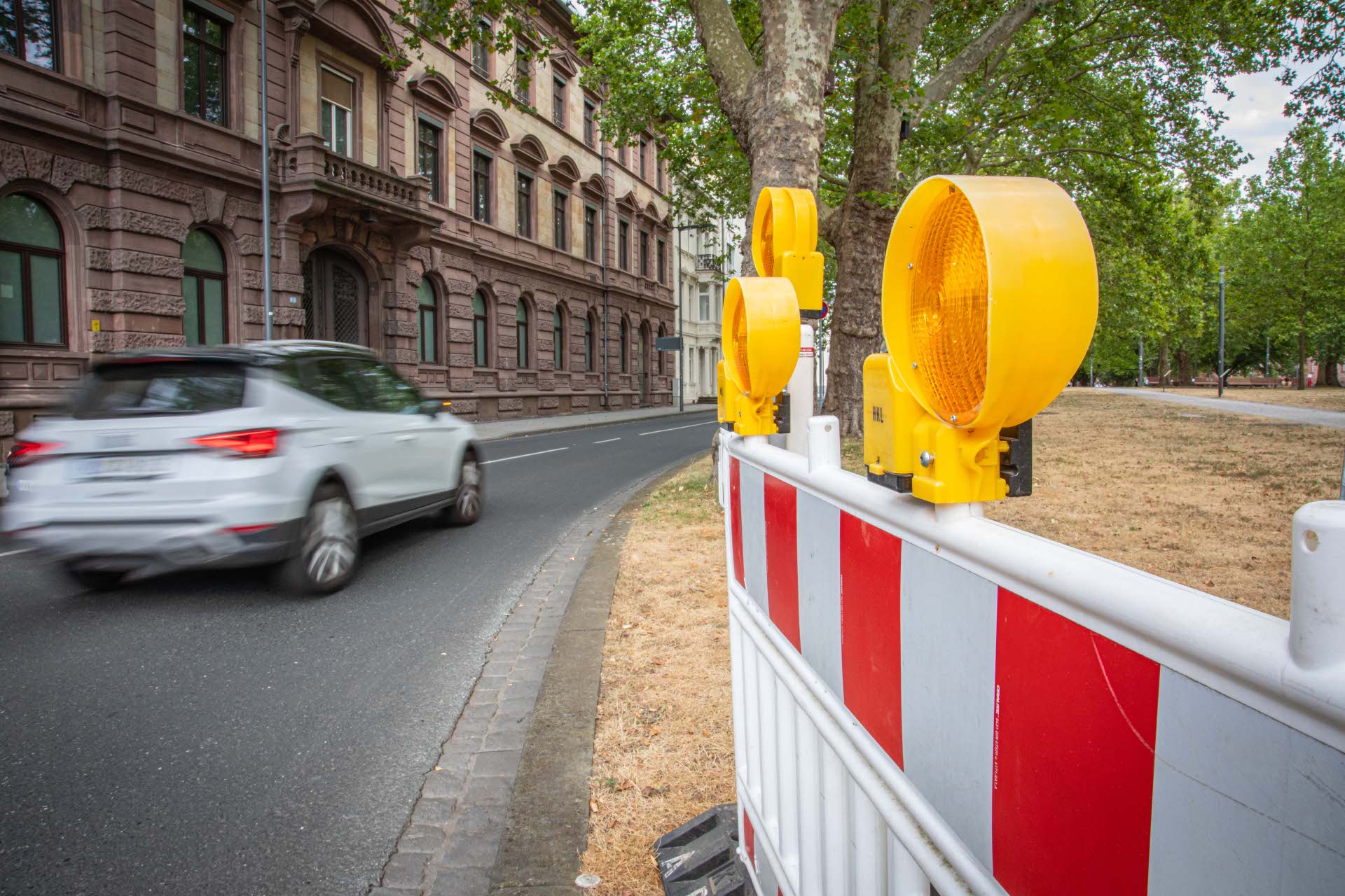 Ein Auto fährt auf einer Straße an einer Absperrung vorbei.