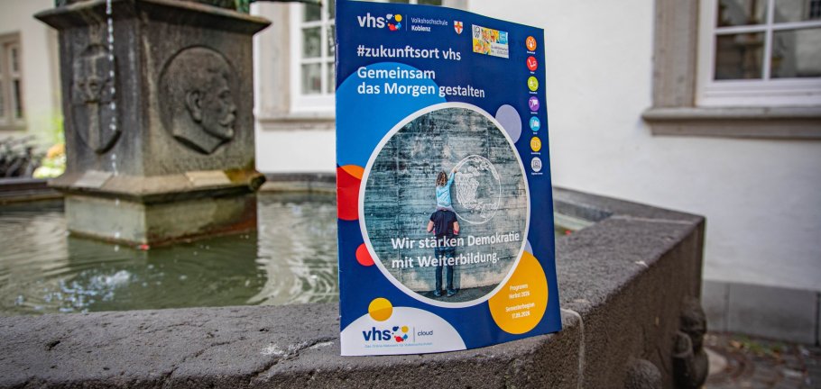 Das neue Programmheft der Volkshochschule Koblenz auf dem Schängelbrunnen