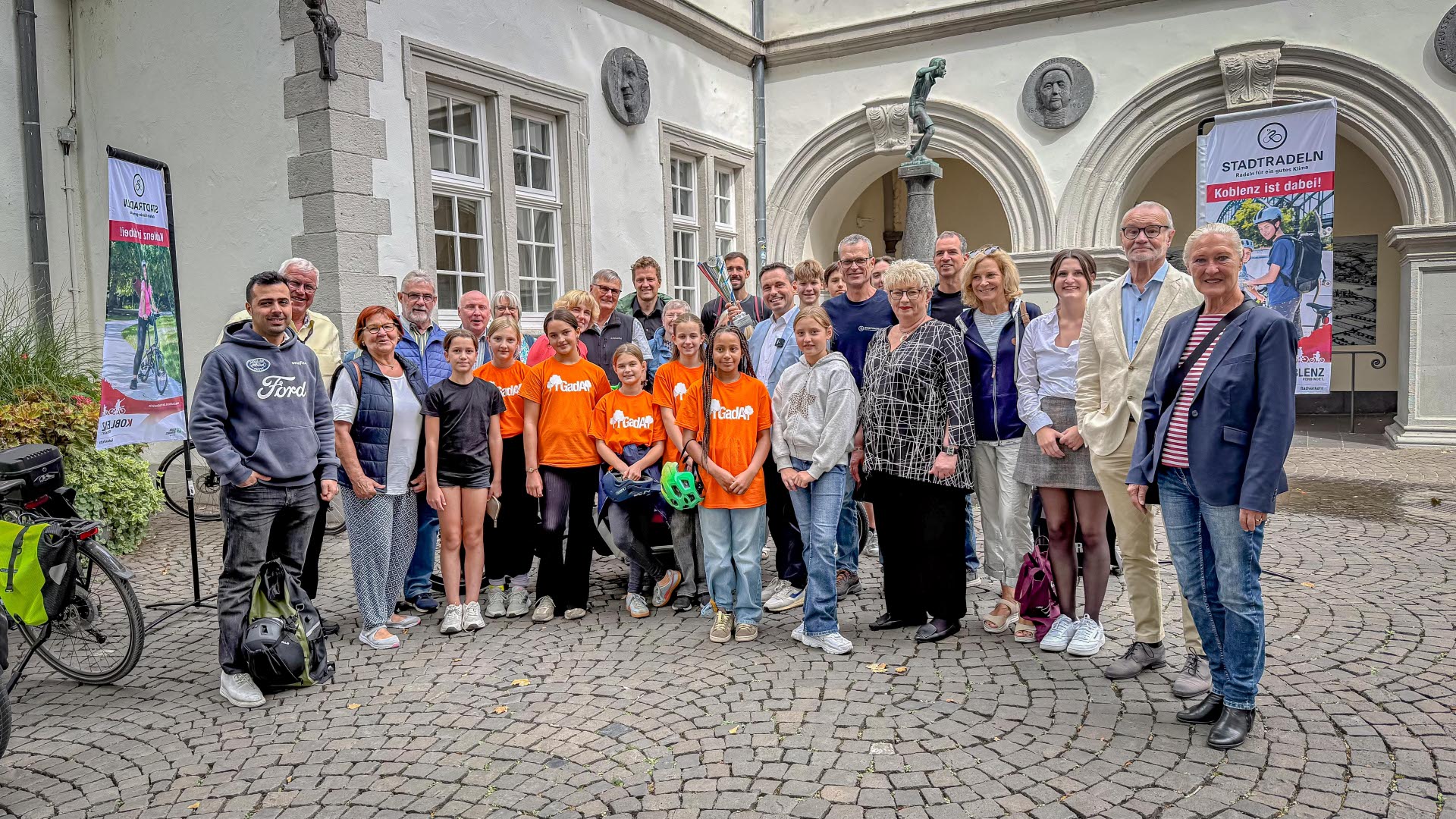 Kinder und Erwachsene stehen vor einem Brunnen.