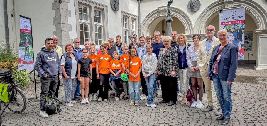 Kinder und Erwachsene stehen vor einem Brunnen.