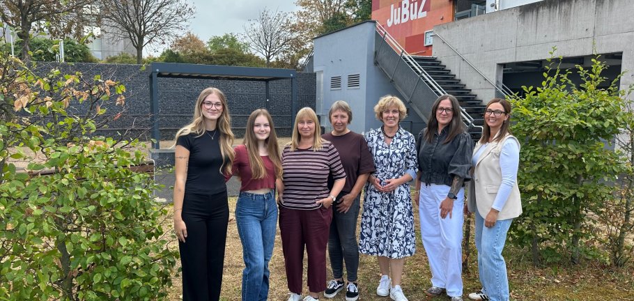 Sieben Frauen stehen für ein Gruppenfoto auf einer Wiese.