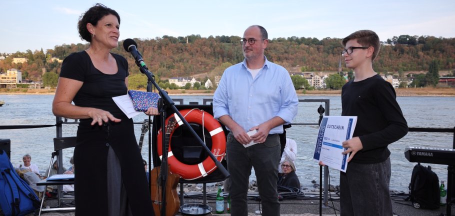 Eine Frau, ein Mann und ein Junge stehen an einem Fluss.