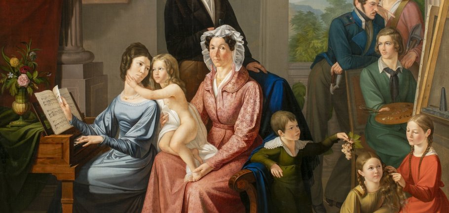 Eine Familie in historischen Gewändern sitzt in einem Raum. Eine Familie in historischen Gewändern sitzt in einem Raum.