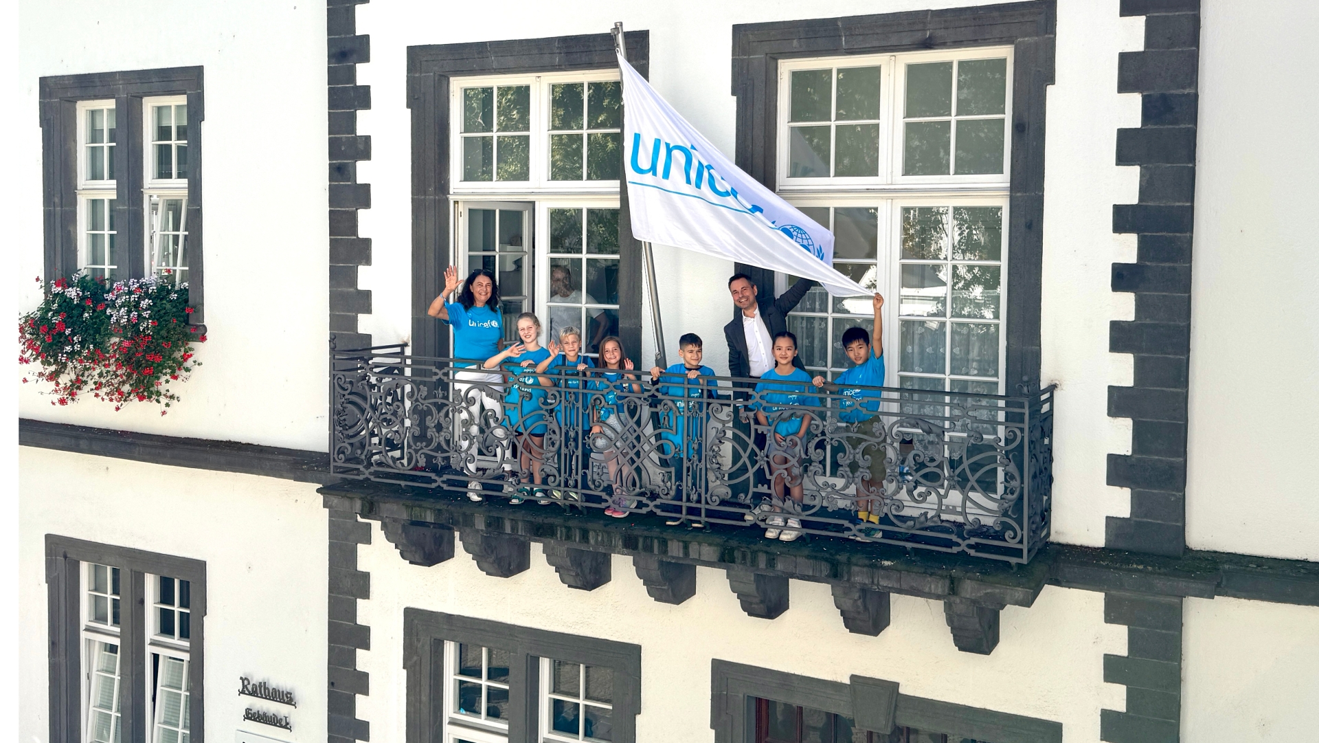 Angelika Markus (links, Vorsitzende der Koblenzer UNICEF-Gruppe) und Oberbürgermeister David Langner (rechts) hissen die UNICEF Flagge mit Schulkindern der Grundschule Rhens und der Pestalozzi-Schule Koblenz am Koblenzer Rathaus.