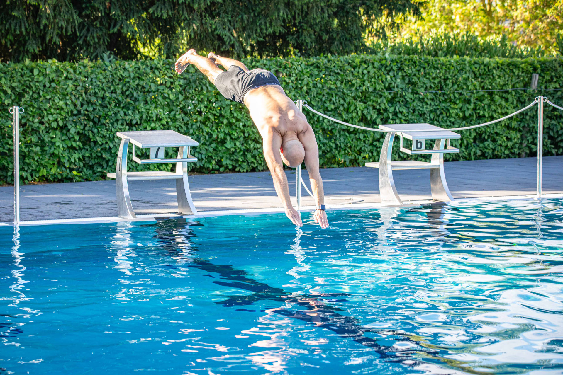 Ein Mann springt in ein Schwimmbecken.