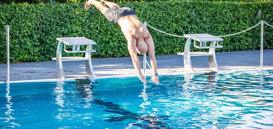 Ein Mann springt in ein Schwimmbecken.