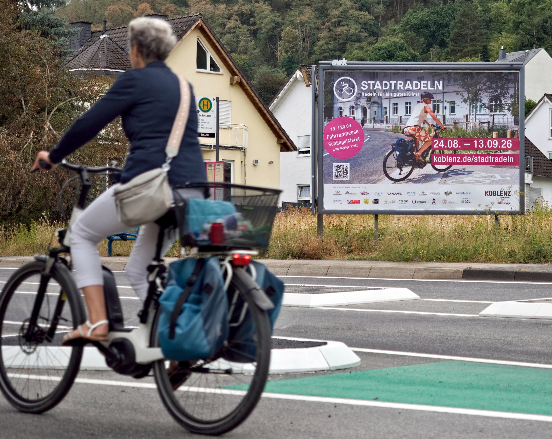 Eine Radfahrerin fährt an einer Plakatwand vorbei.