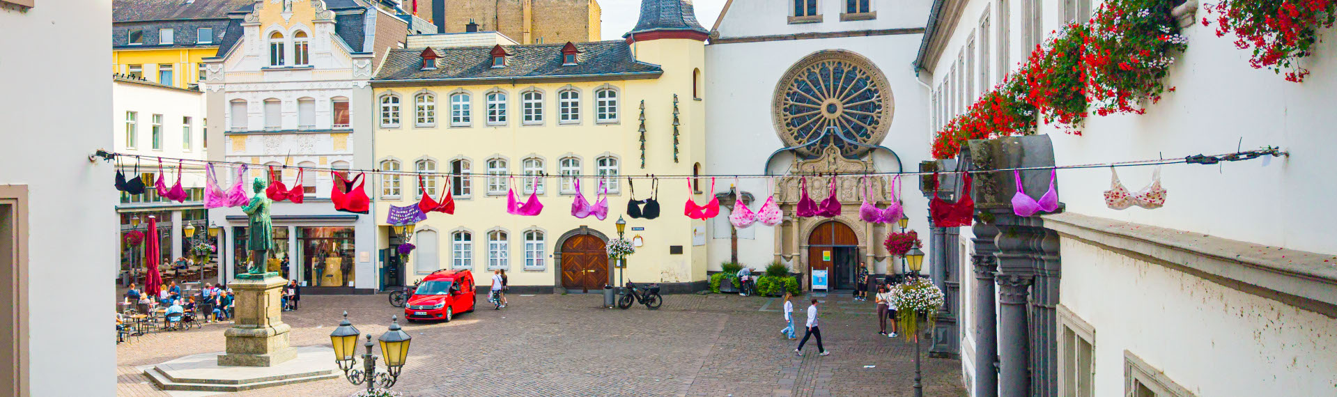 Pinke BHs hängen an einer Leine über einer Straße.
