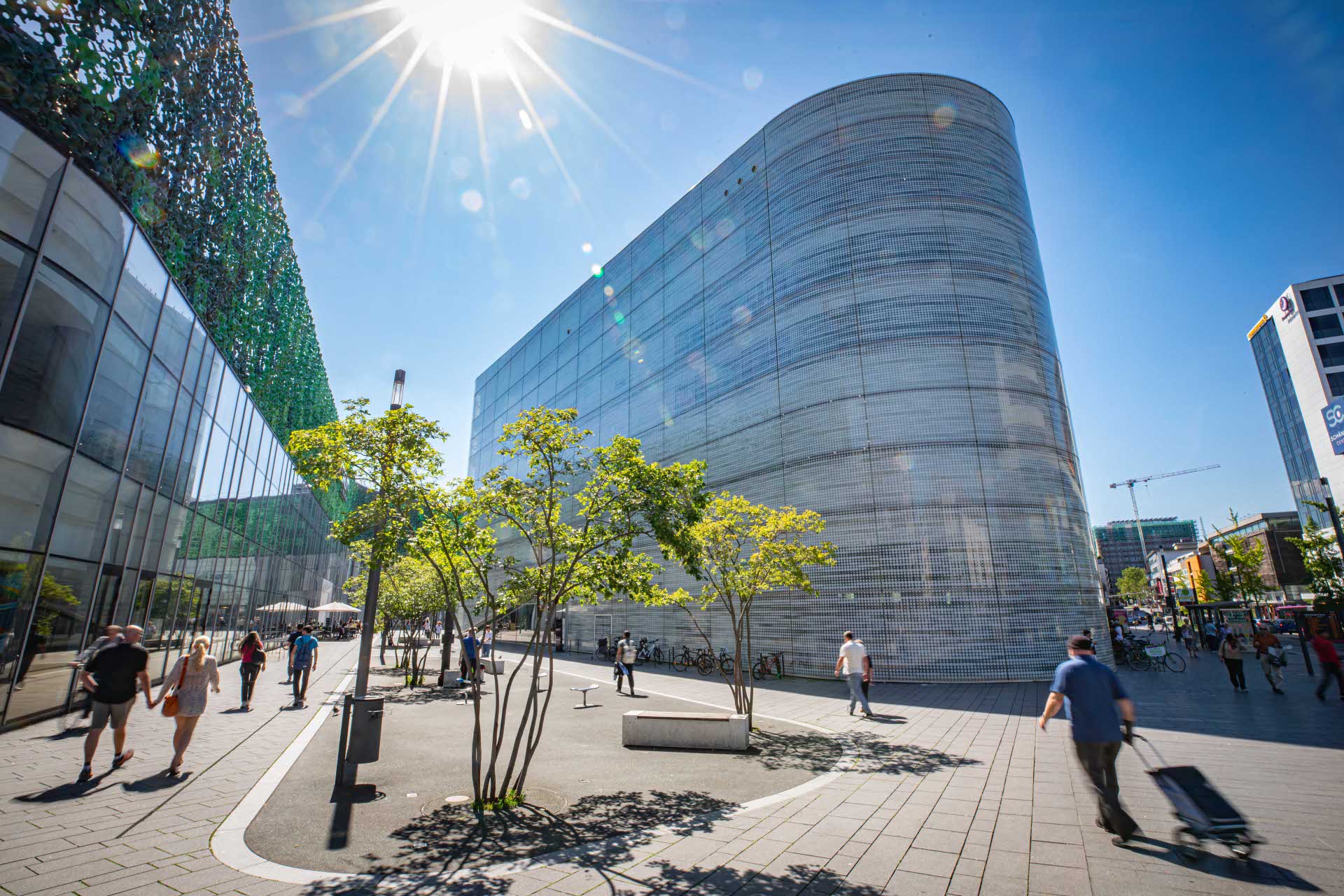 Ein Gebäude mit einer Glasfront steht auf einem belebten Platz.