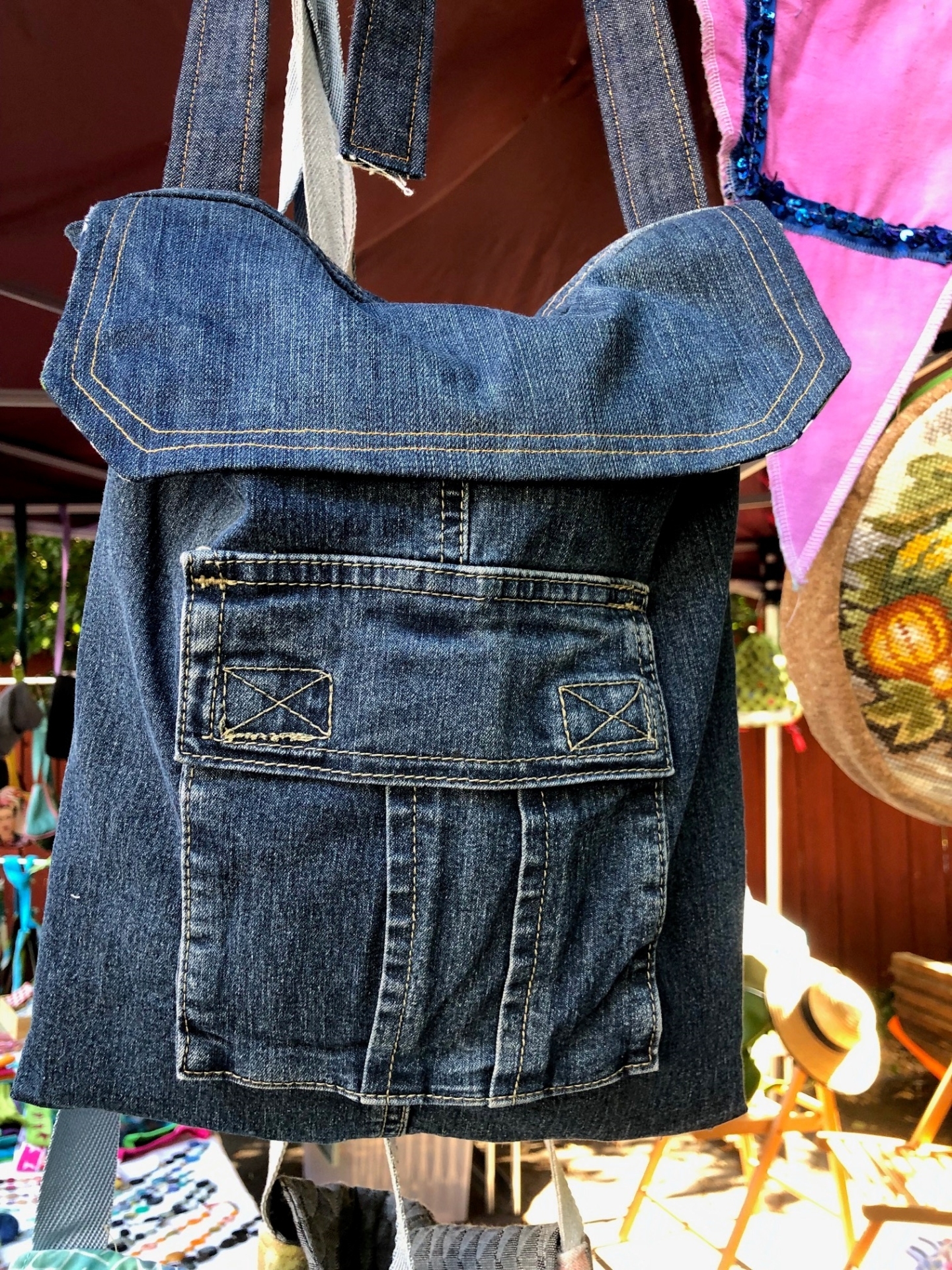 Ein Rucksack aus Jeans-Stoff hängt an einem Stand.