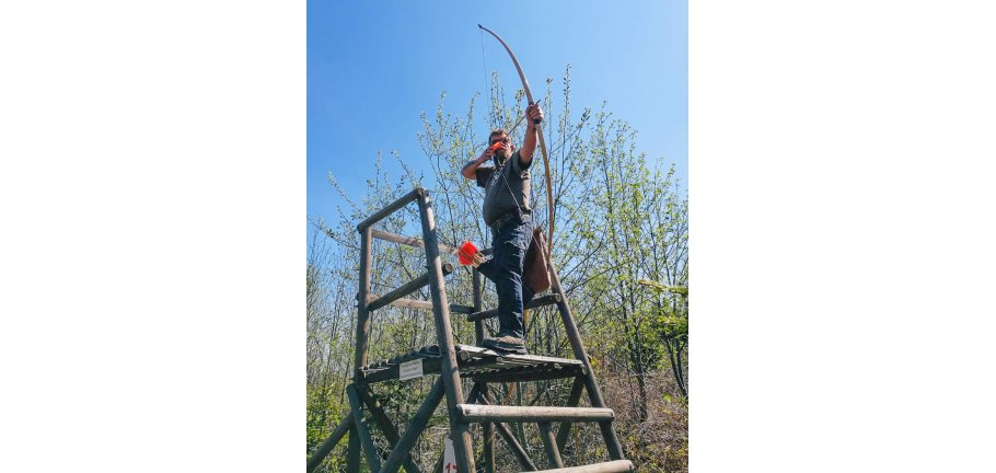 Ein Bogenschütz steht mit seinem gespannten Bogen auf einem Hochsitz. Ein Bogenschütz steht mit seinem gespannten Bogen auf einem Hochsitz.