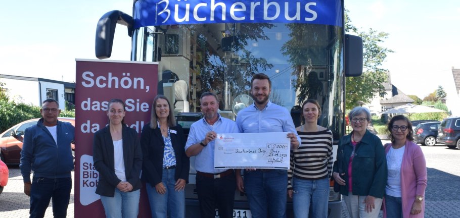 Mehrere Personen stehen vor einem Bus. Mehrere Personen stehen vor einem Bus.