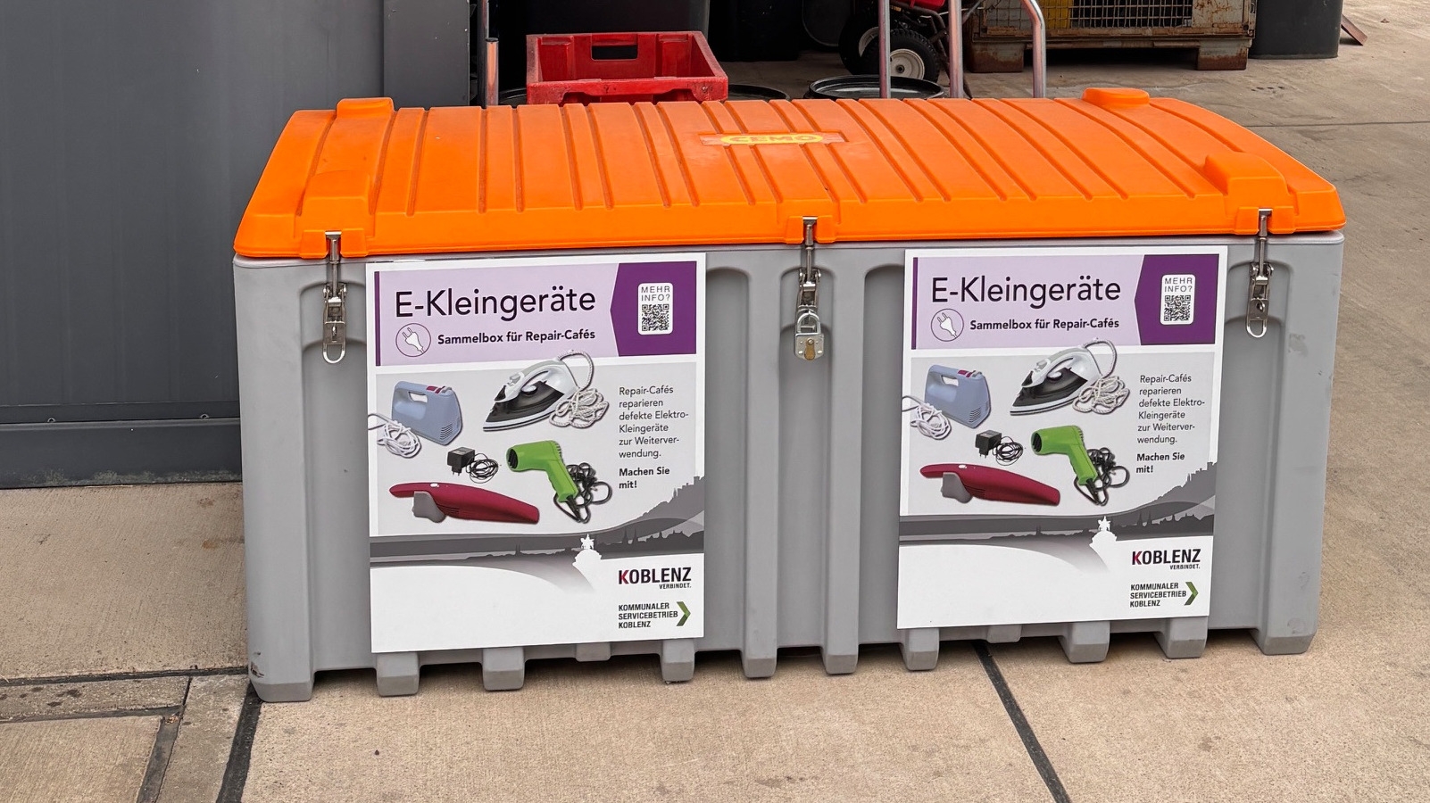 Eine Box zum Sammeln von Elektrokleingeräten steht an einer Wand.