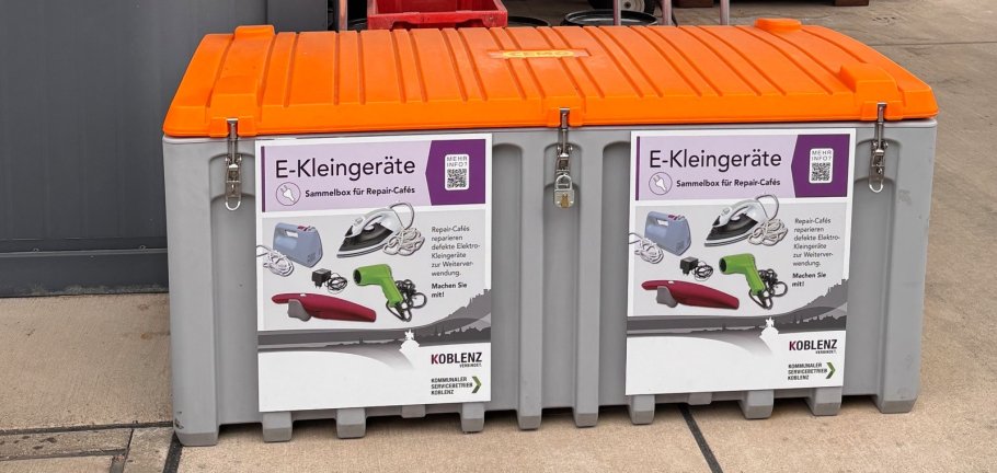 Eine Box zum Sammeln von Elektrokleingeräten steht an einer Wand. Eine Box zum Sammeln von Elektrokleingeräten steht an einer Wand.
