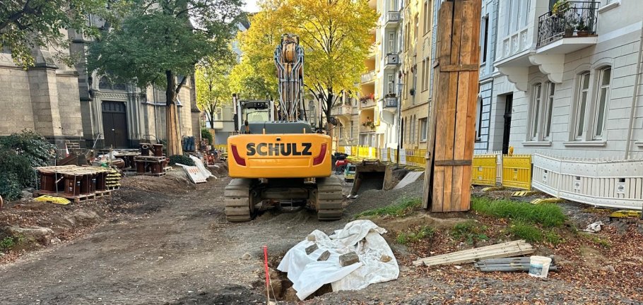 Ein Bagger steht auf einer Straßenbaustelle an einem Baum. Ein Bagger steht auf einer Straßenbaustelle an einem Baum.