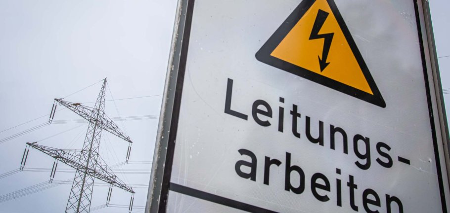 Stromleitungen sind hinter einem Hinweisschild zu sehen. Stromleitungen sind hinter einem Hinweisschild zu sehen.