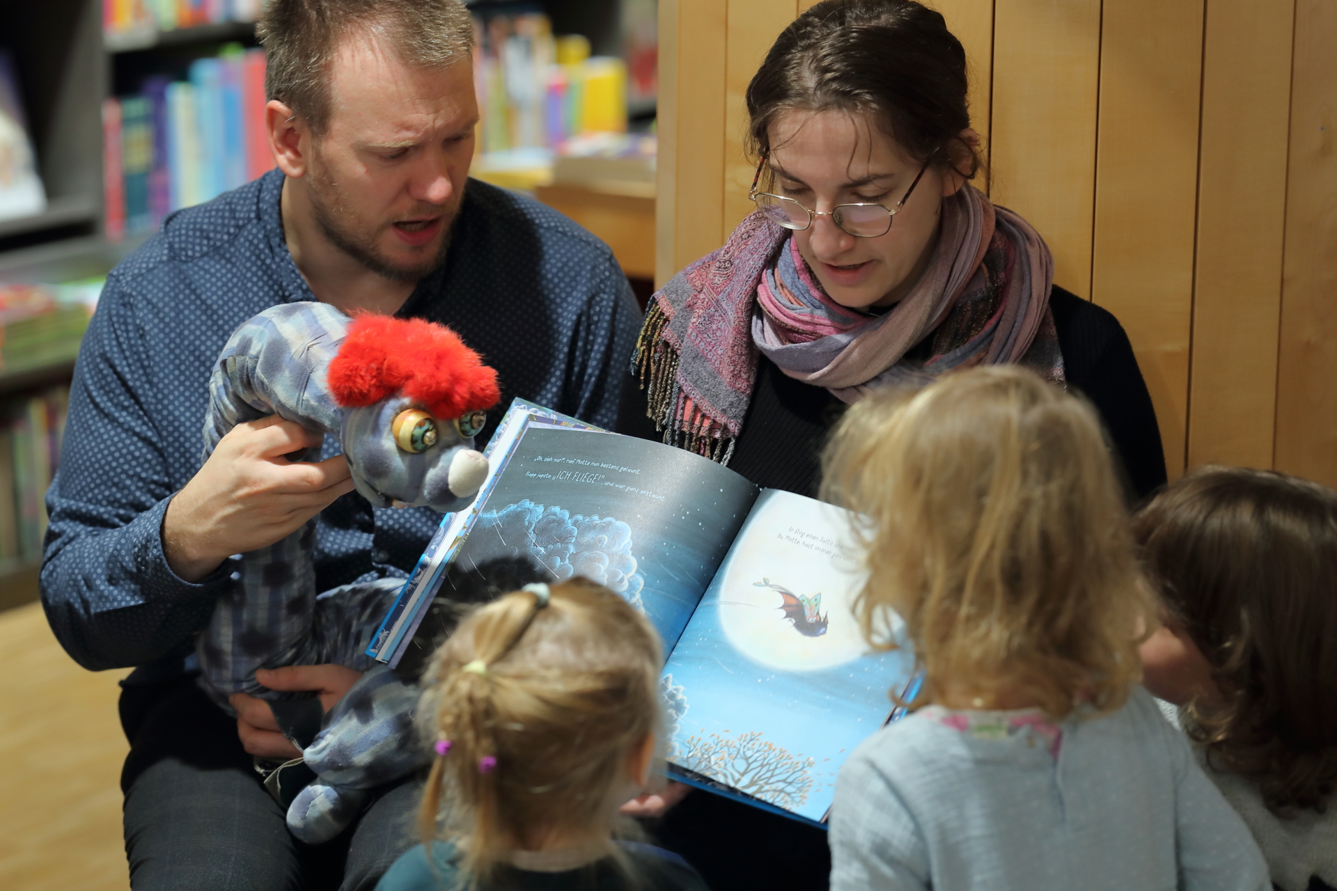Kinder sitzen vor einem Buch und bekommen eine Geschichte erzählt.