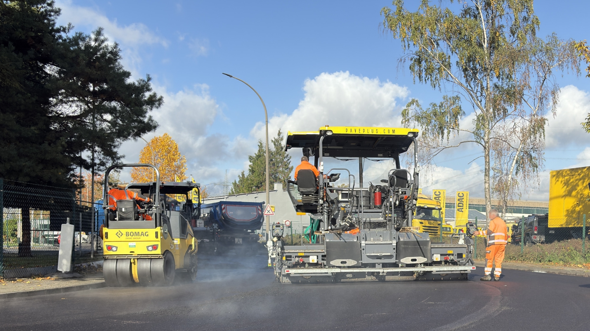 Auf einer Straße wird mit Baumaschinen Asphalt eingebracht.