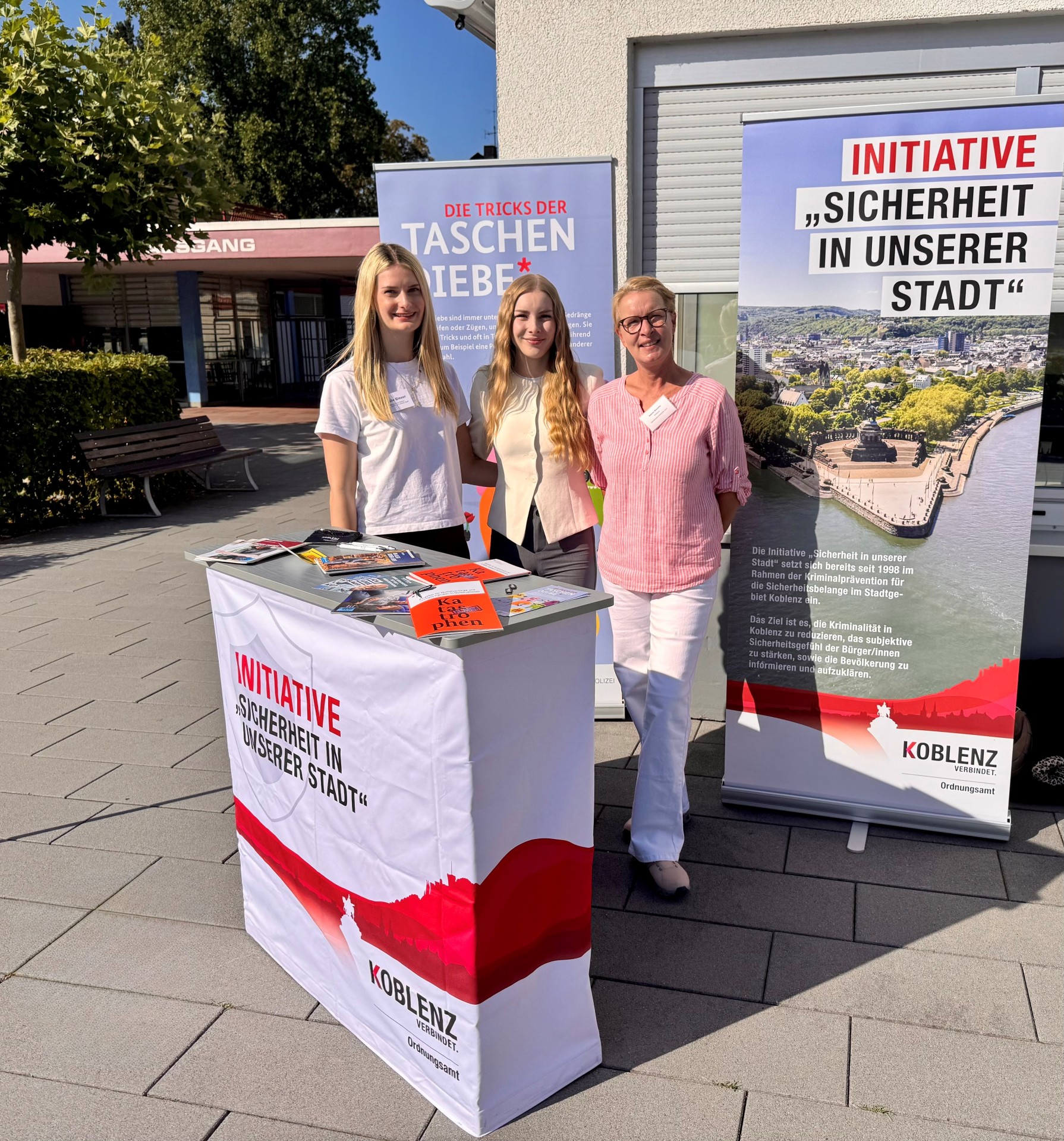 Drei Frauen stehen an einem Informationsstand.