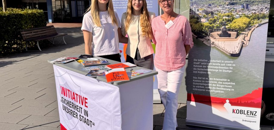 Drei Frauen stehen an einem Informationsstand. Drei Frauen stehen an einem Informationsstand.