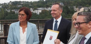 Bürgermeisterin Dr. Margit Theis-Scholz präsentiert den von Bundesverkehrsminister ausgehändigten Förderbescheid zum Ausbau des Geh- und Radweges auf der Horchheimer Eisenbahnbrücke Bürgermeisterin Dr. Margit Theis-Scholz präsentiert den von Bundesverkehrsminister ausgehändigten Förderbescheid zum Ausbau des Geh- und Radweges auf der Horchheimer Eisenbahnbrücke